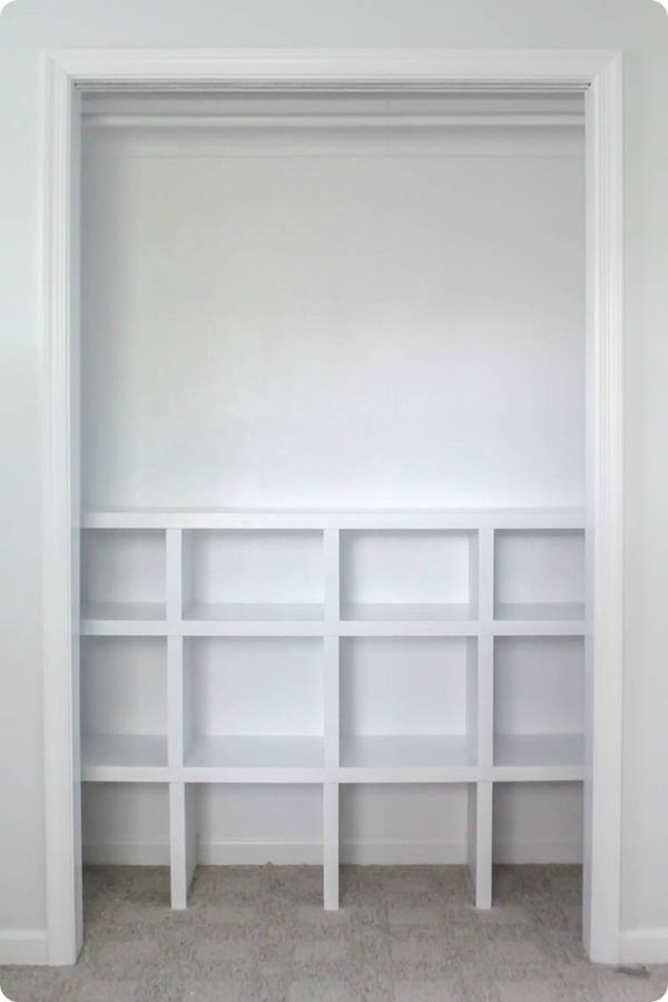 an empty white bookcase in the corner of a room with no one on it