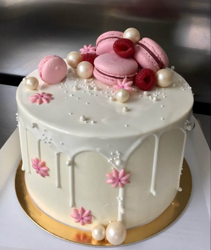 a white cake with pink frosting and macaroons on top