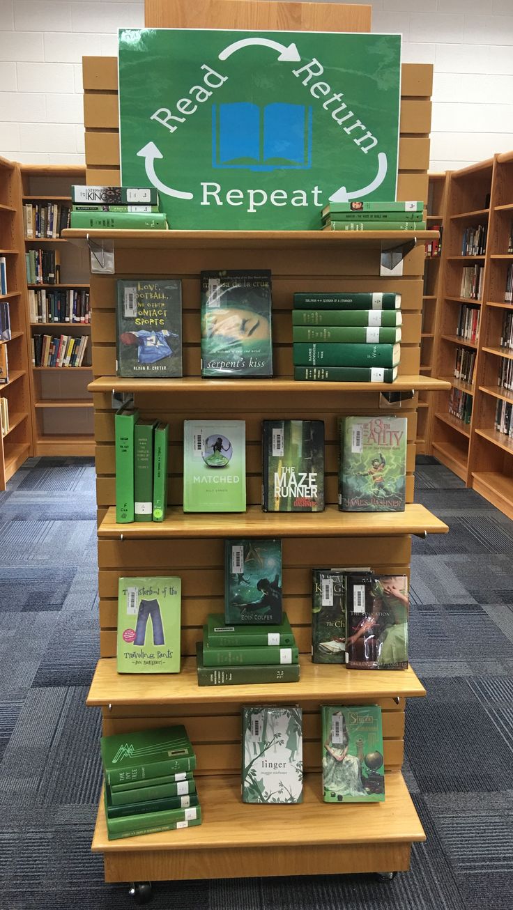 there are many books on the shelves in the library and one has a sign that says read again repeat