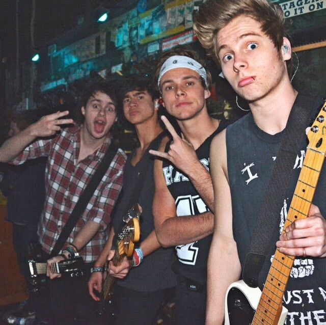 a group of young men standing next to each other with guitars in front of them