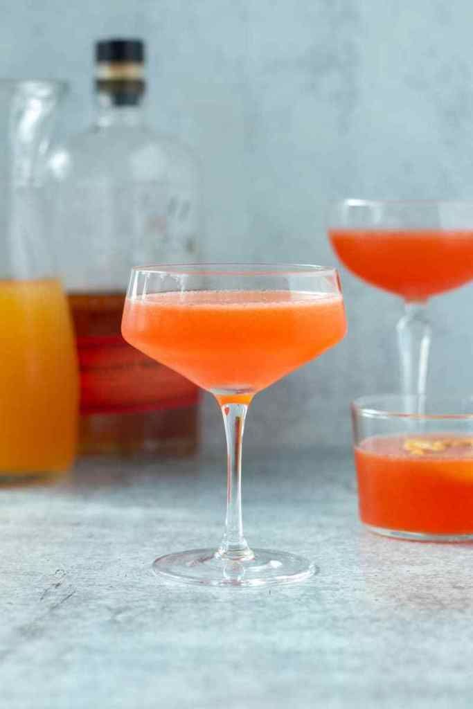 two cocktail glasses filled with orange juice and garnished with an orange slice