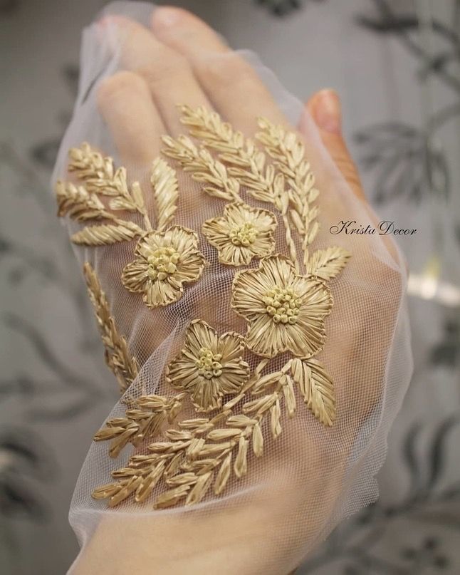 a woman's hand is adorned with gold flowers and mesh gloves that have been embroidered onto them