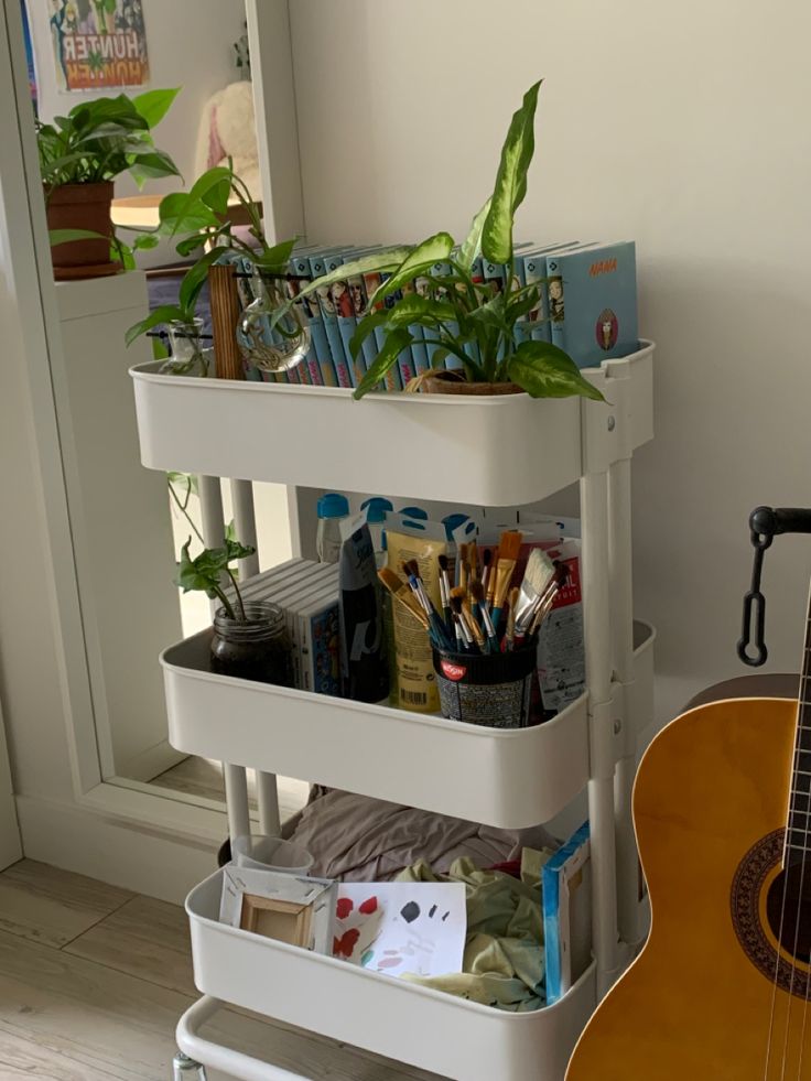 a guitar sits next to a white cart with plants on it