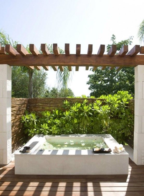 an outdoor jacuzzi tub in the middle of a wooden deck with plants on it