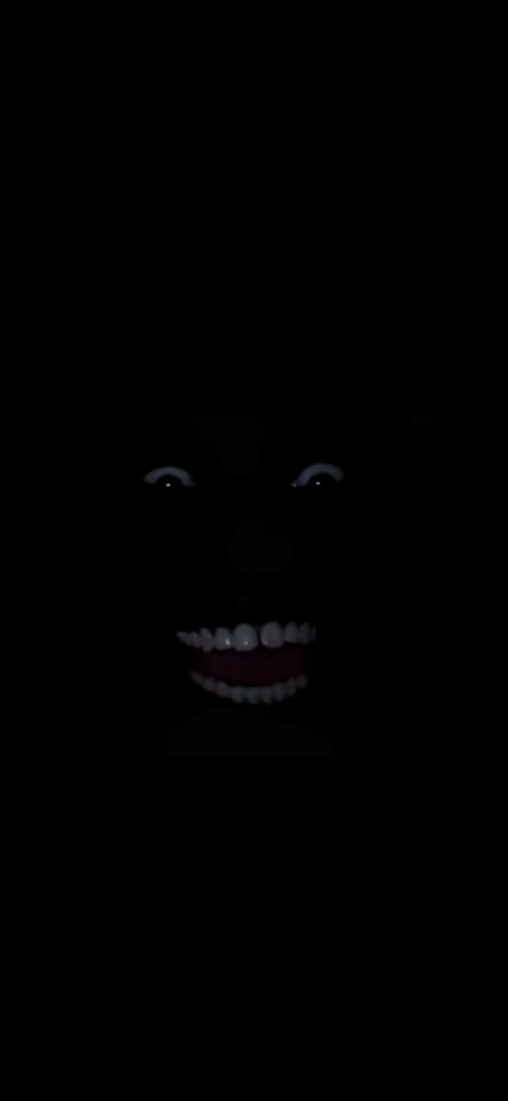 a creepy clown's face is lit up in the dark