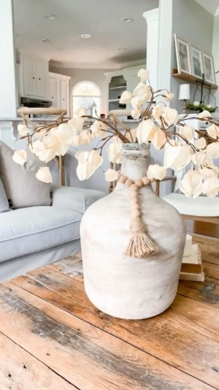 a vase with flowers in it sitting on a table next to a couch and coffee table