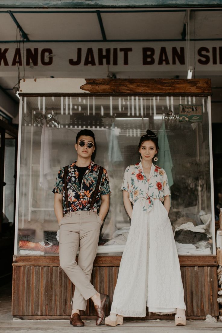 two people standing in front of a food stand with their hands on their hipss