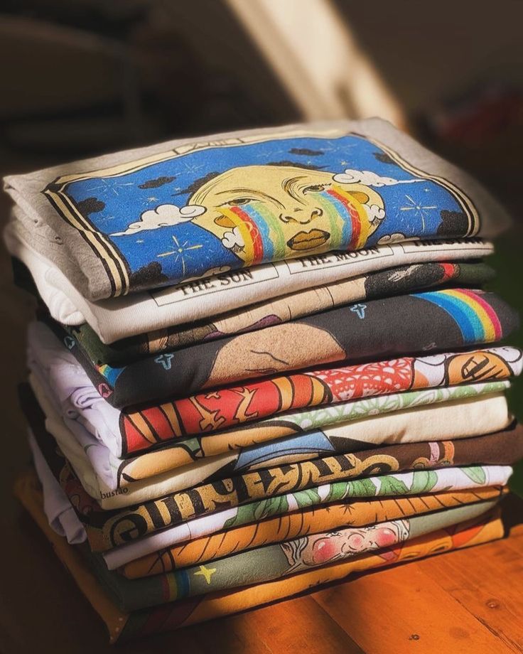 a stack of t - shirts sitting on top of a wooden table