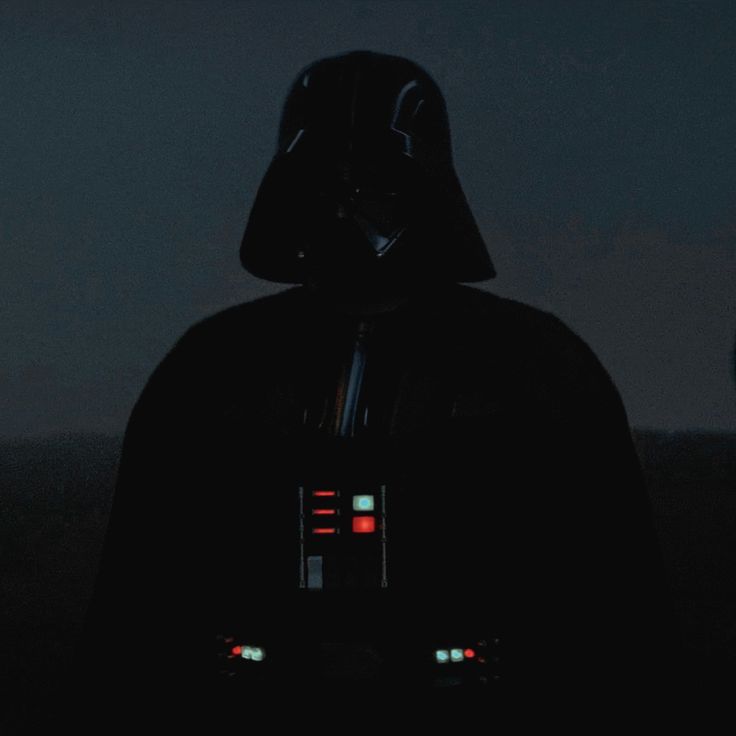 a darth vader in the dark with his lights on, looking at something