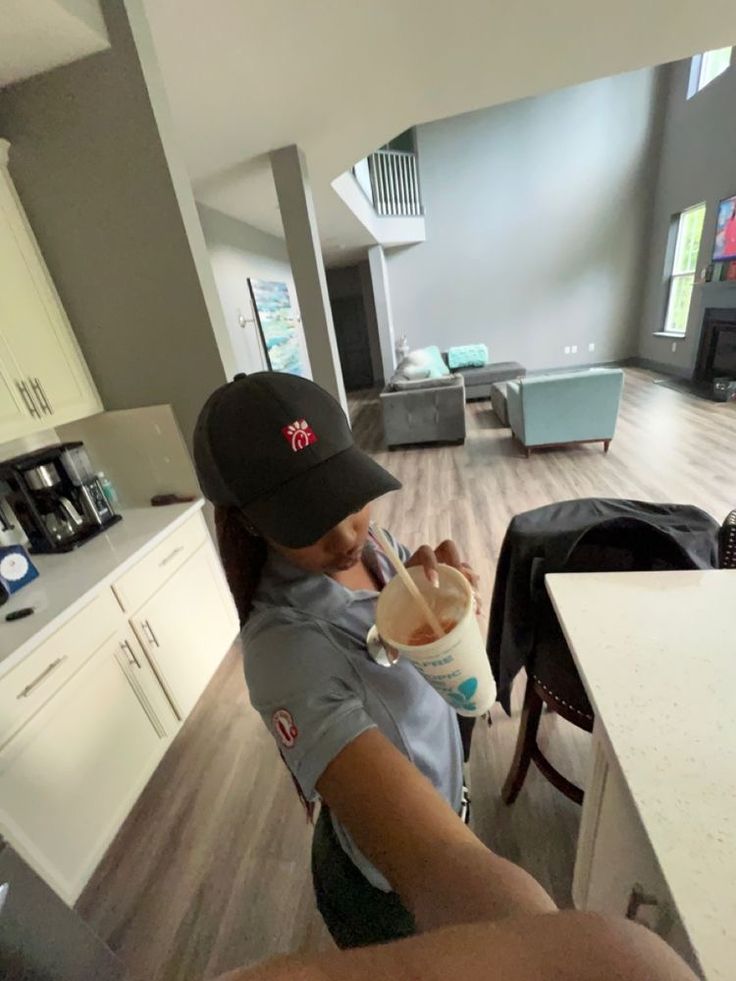 a person sitting at a kitchen counter drinking from a cup