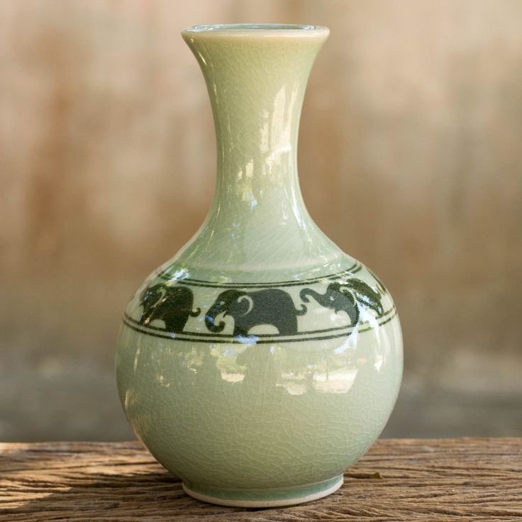 a green vase sitting on top of a wooden table