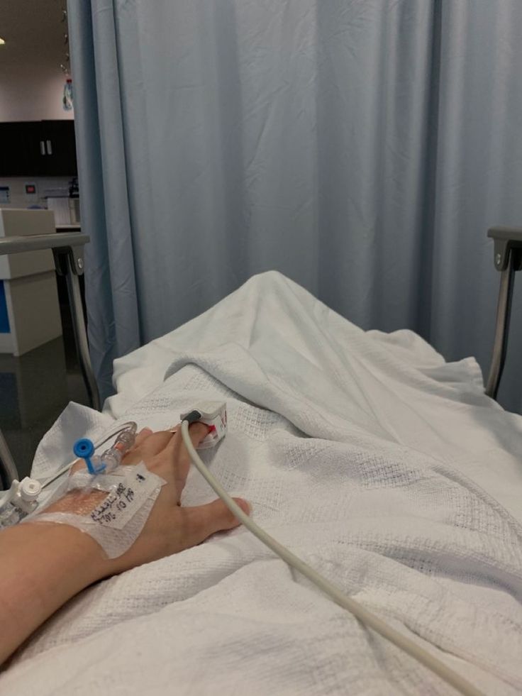 a person laying in a hospital bed with an oxygen tube attached to their arm and hand