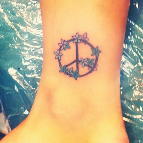 a small peace sign tattoo on the ankle