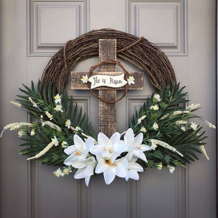 a wreath with flowers and a cross on the front door