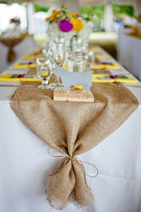 the table is decorated with burlap and silver place settings, along with napkins