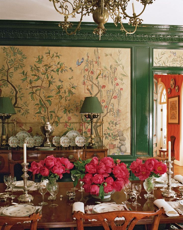 a dining room table with red flowers in vases