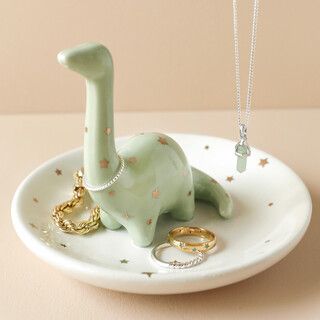 an elephant figurine sitting on top of a plate next to two wedding rings