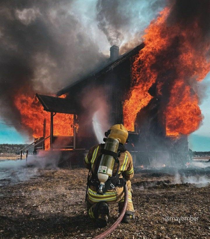 a firefighter kneeling down in front of a burning house