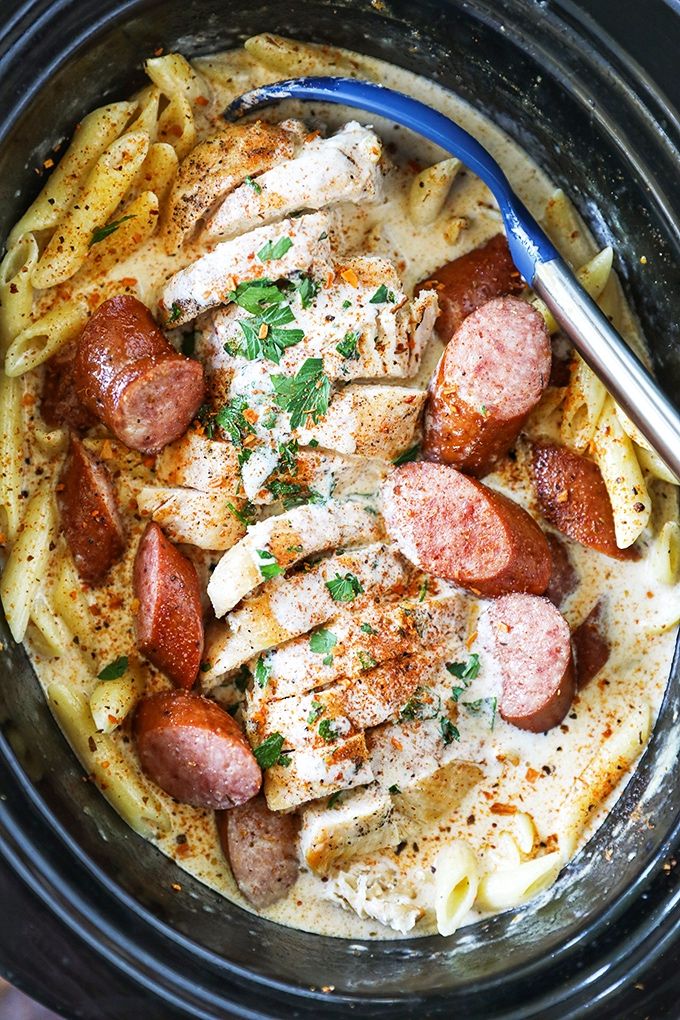 a crock pot filled with sausage and pasta