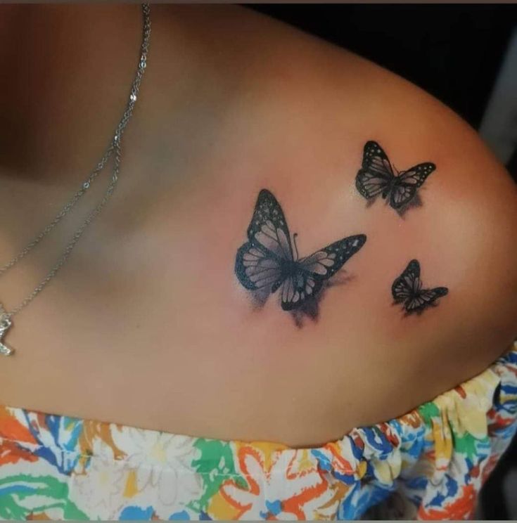 three butterflies on the back of a woman's shoulder