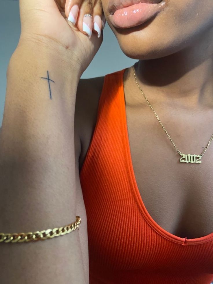 a woman with a cross tattoo on her left arm, wearing an orange tank top