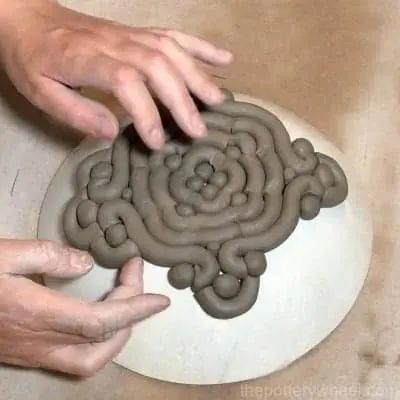 two hands reaching for an object made out of clay