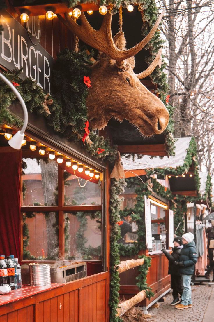 a moose head mounted to the side of a building next to people walking down a street