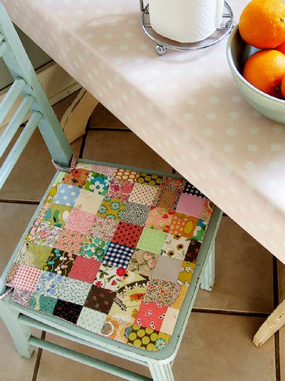 a bowl of oranges sitting on top of a table next to a cloth covered chair