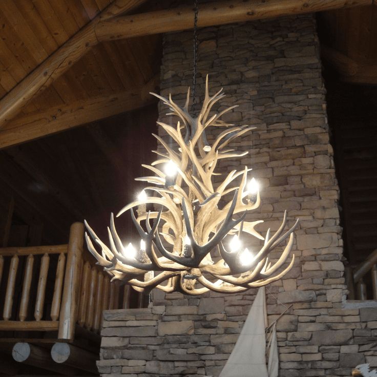 a chandelier made out of antlers hangs from the ceiling in a living room