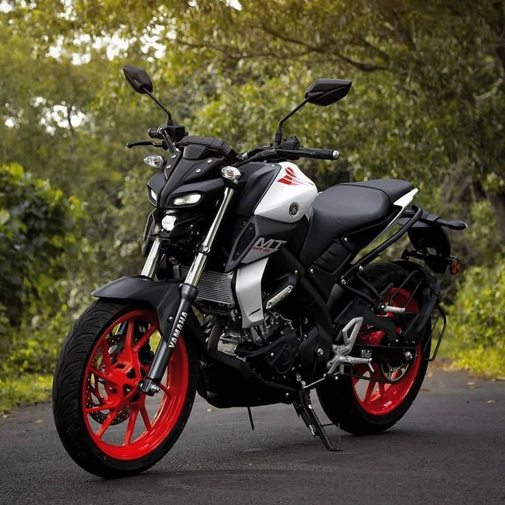 a black and silver motorcycle parked on the side of a road with red rims