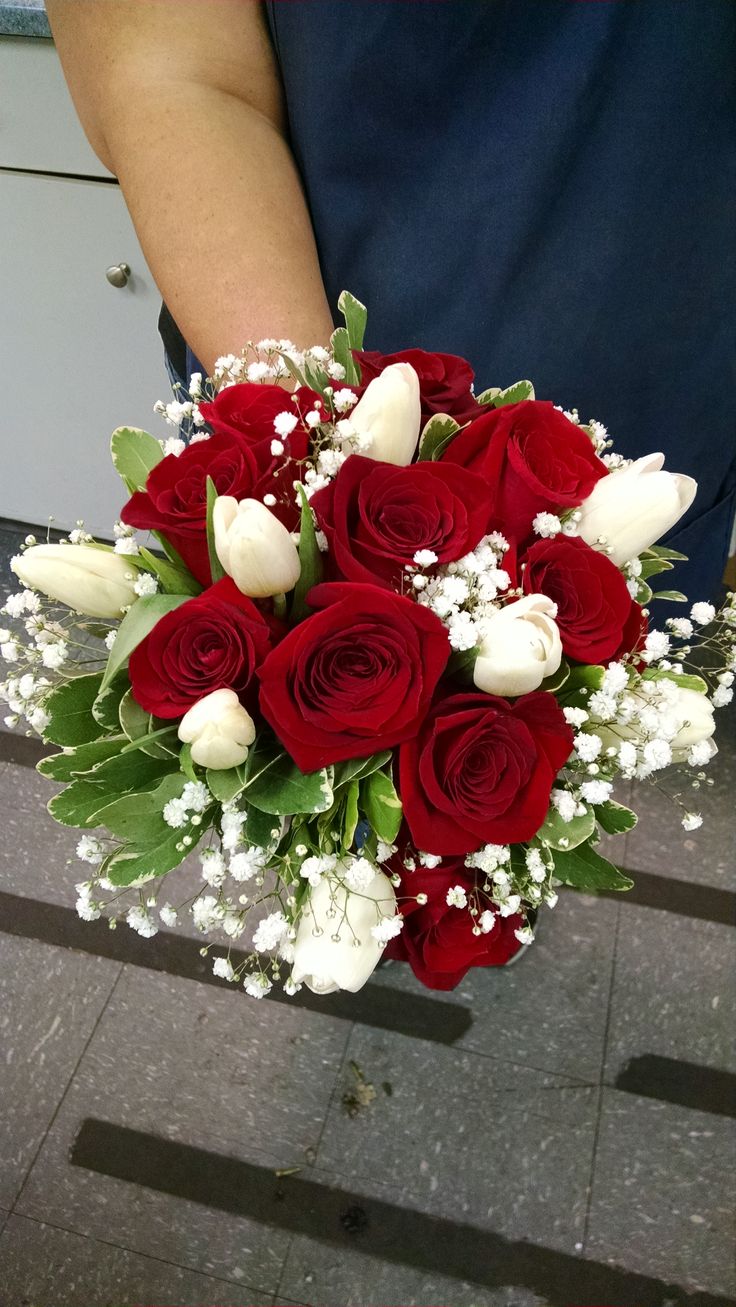 someone holding a bouquet of red and white roses