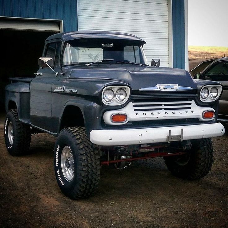 an old pick up truck parked in front of a garage