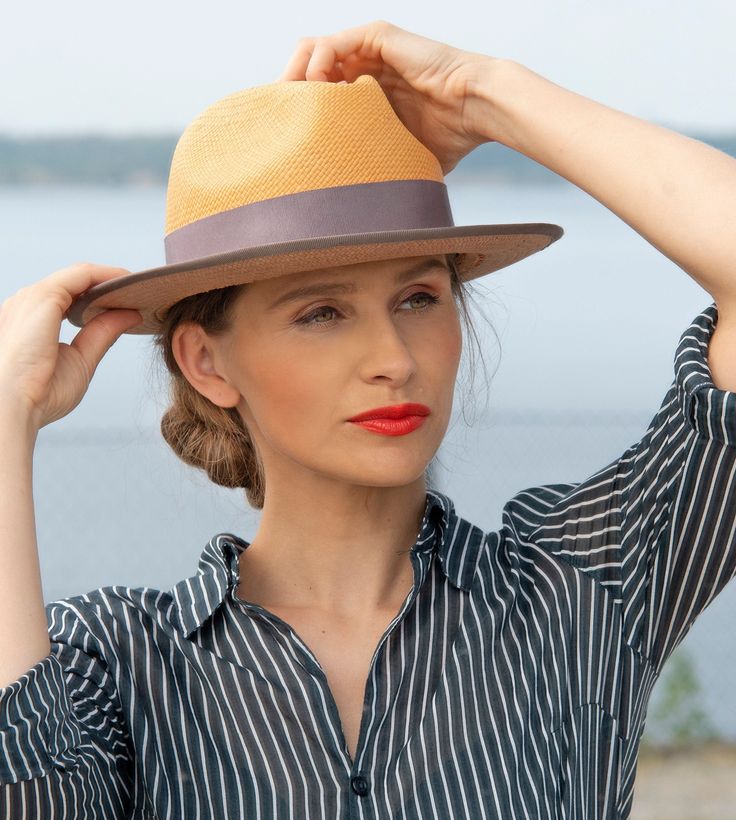 "Elven" is a hand-woven fedora made from the fibres of the toquilla palm tree. With its classic hat shape, this elegant summer hat pleasantly shields you from the sun and heat. Lightweight and air-permeable. The sun-yellow fibres blend into a delicate "mauve". The hat band and the hat brim edged by hand with a narrow ribbed band pick up the colour tone.  Careful craftsmanship and the highest quality in material and design offer optimal wearing comfort. The androgynous ladies' hat was elaborately Handwoven Adjustable Fedora For Summer, Adjustable Handwoven Fedora For Summer, Summer Fedora With Handwoven Flat Brim, Handwoven Short Brim Straw Hat, Summer Handwoven Fedora With Flat Brim, Braided Flat Brim Fedora, Summer Adjustable Handwoven Fedora, Spring Handwoven Toquilla Straw Fedora, Adjustable Handwoven Summer Fedora