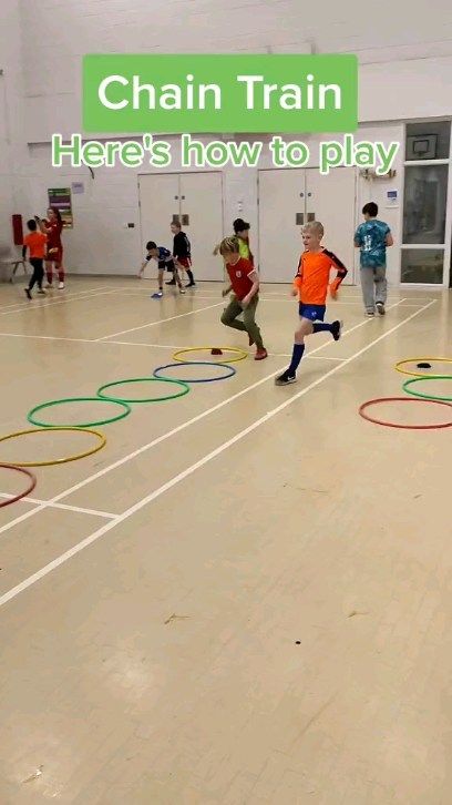 there are many children playing with hoop rings in an indoor gym area that is painted white and has the words chain train here's how to play