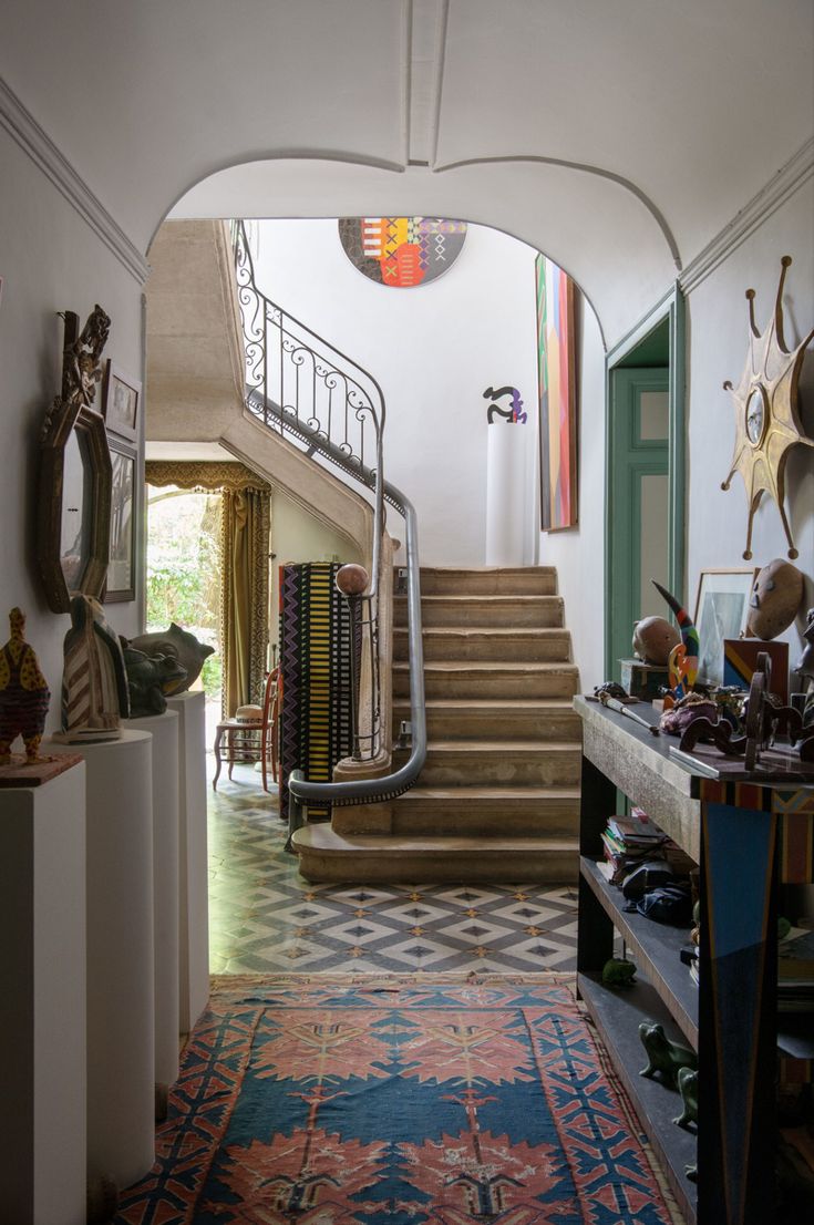 the hallway is decorated with colorful rugs and art on the walls, along with an ornate staircase