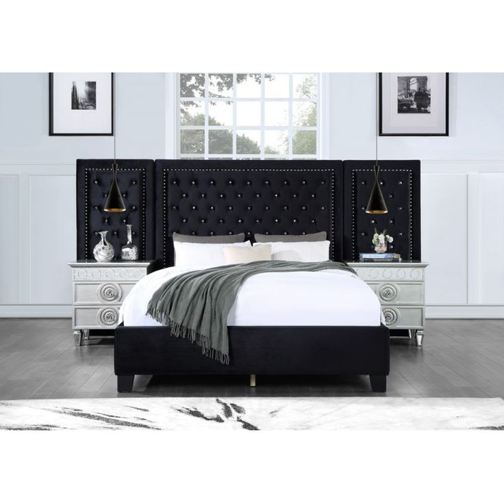 a bed with black headboard and foot board in a white room next to pictures on the wall