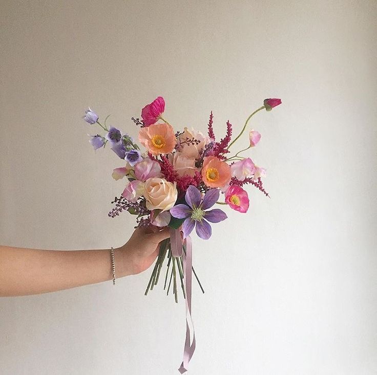 a person holding a bouquet of flowers in their hand with the other hand on it