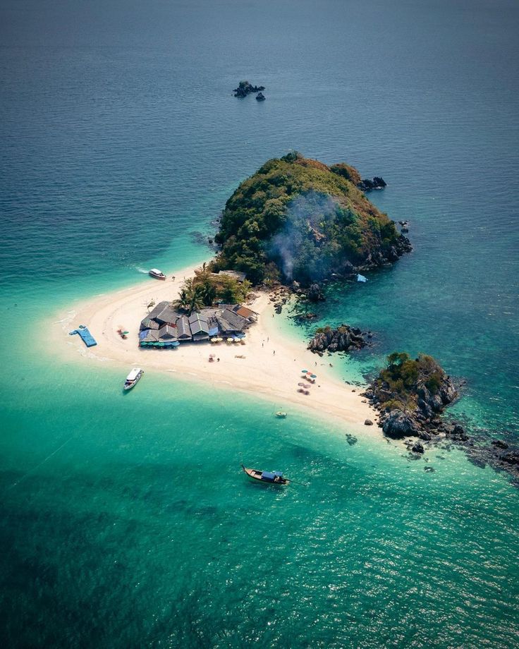 an island in the middle of the ocean with boats floating on it's shore