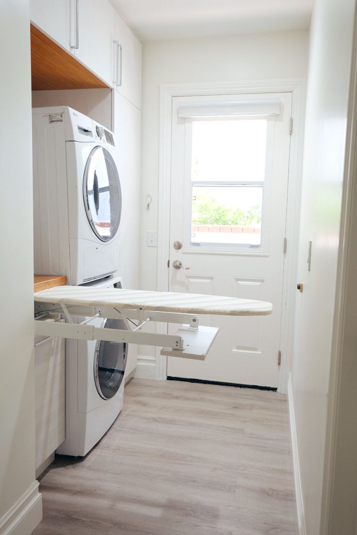 a washer and dryer in a small room with wood flooring on the side