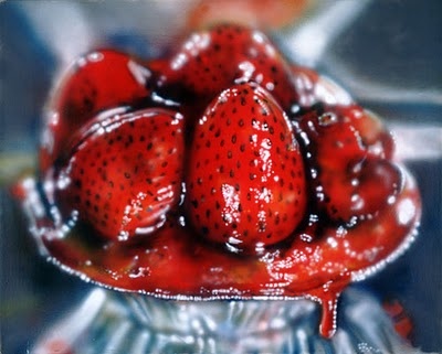 some strawberries are in a silver bowl with sauce on top and the bottom half is drizzled