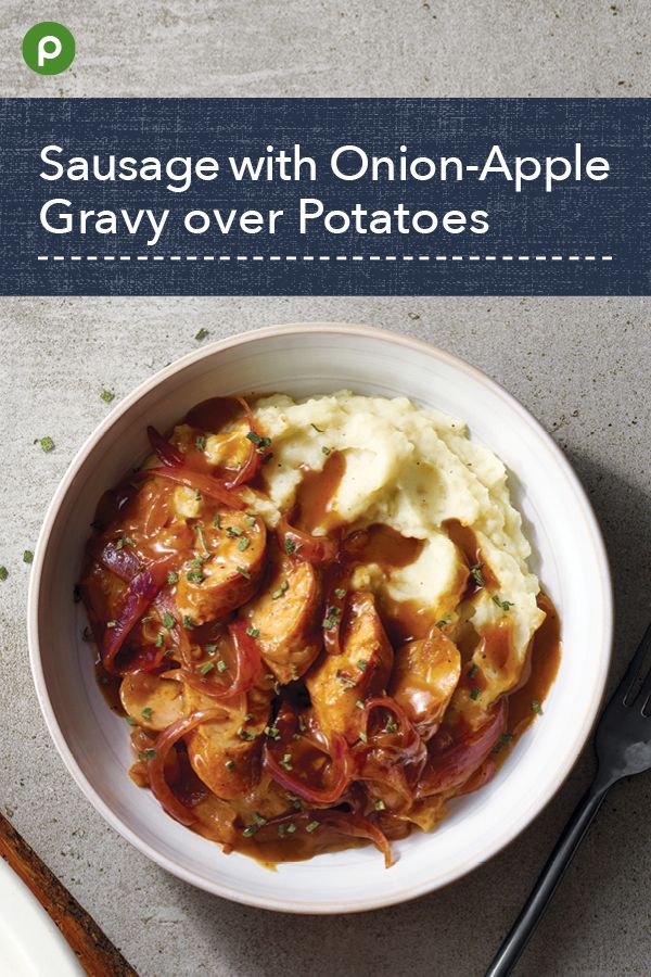 sausage with onion - apple gravy over potatoes in a white bowl on a table