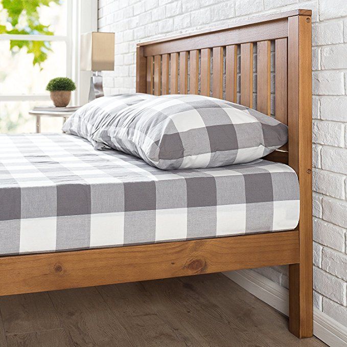 a bed with pillows on top of it next to a brick wall and potted plant