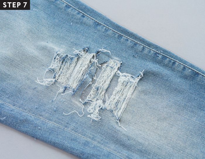 an old pair of blue jeans with holes in the side and torn off fabric on top