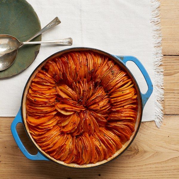 a pot filled with food sitting on top of a wooden table next to a spoon