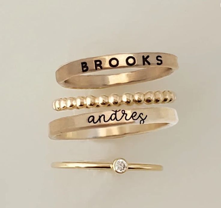 This exquisite personalized ring set is a beautiful way to show your loved one just how special they are. Crafted from high-quality .999 fine silver, 14k yellow gold filled, or 14k rose gold filled, each ring is adorned with a sparkling cubic zirconia stone and can be personalized with a special message. Whether you're celebrating a milestone, expressing your love, or just wanting to make a unique statement, this ring set is the perfect way to do it. With its timeless beauty and thoughtful customization, it's sure to be a cherished piece for years to come. This listing includes 4 rings: - two name rings in your choice of font (see photos and drop down menu for choices) - a thin cz ring - a beaded spacer ring These rings are handmade in our Indiana studio. We use yellow gold solder on our r Personalized Stackable Rings, Stackable Name Rings, Rings Personalized, Seashell Projects, Mom Ring, Name Ring, Mother Rings, Name Rings, Mom Jewelry