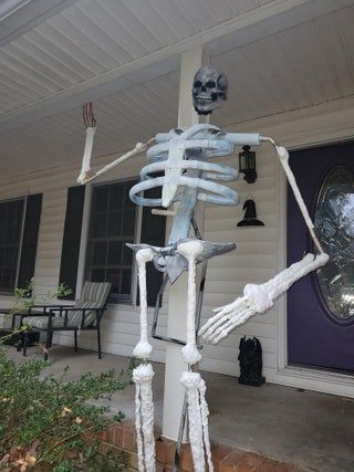 a skeleton standing in front of a house