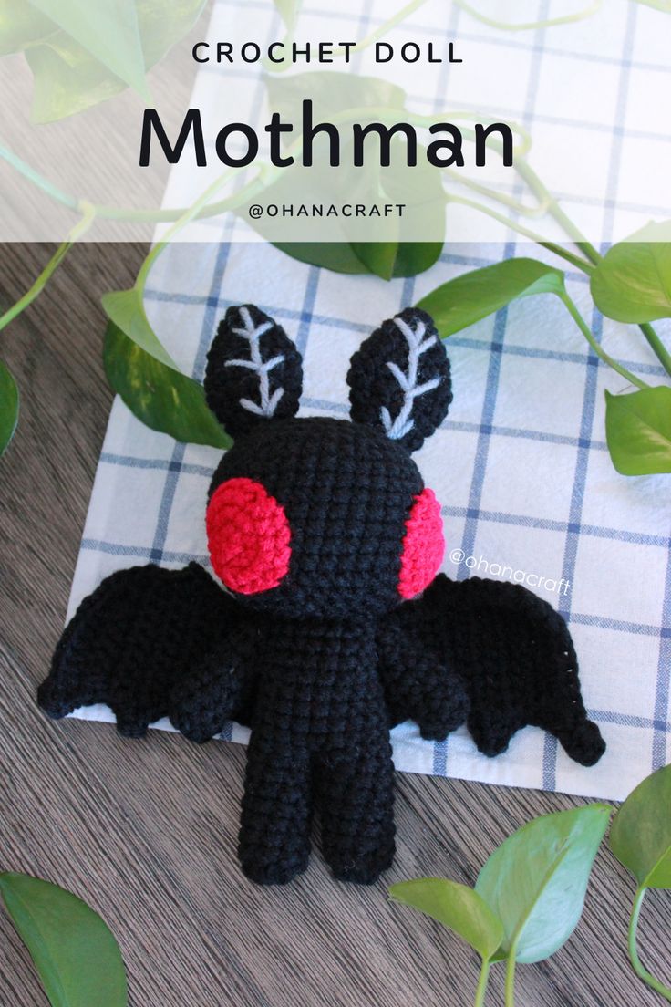 a crocheted stuffed animal sitting on top of a table next to green leaves