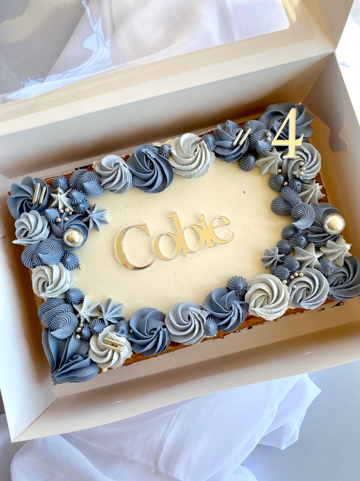 a cake in a box with the number four on it's side and decorated with seashells