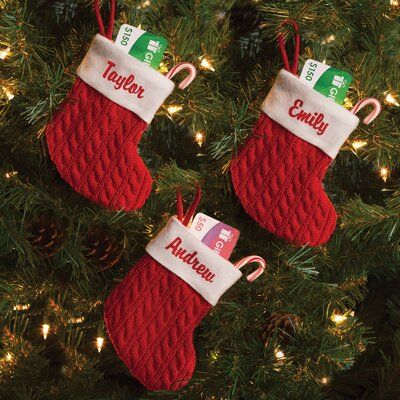 three stockings hanging from a christmas tree decorated with candy canes and personalized name tags