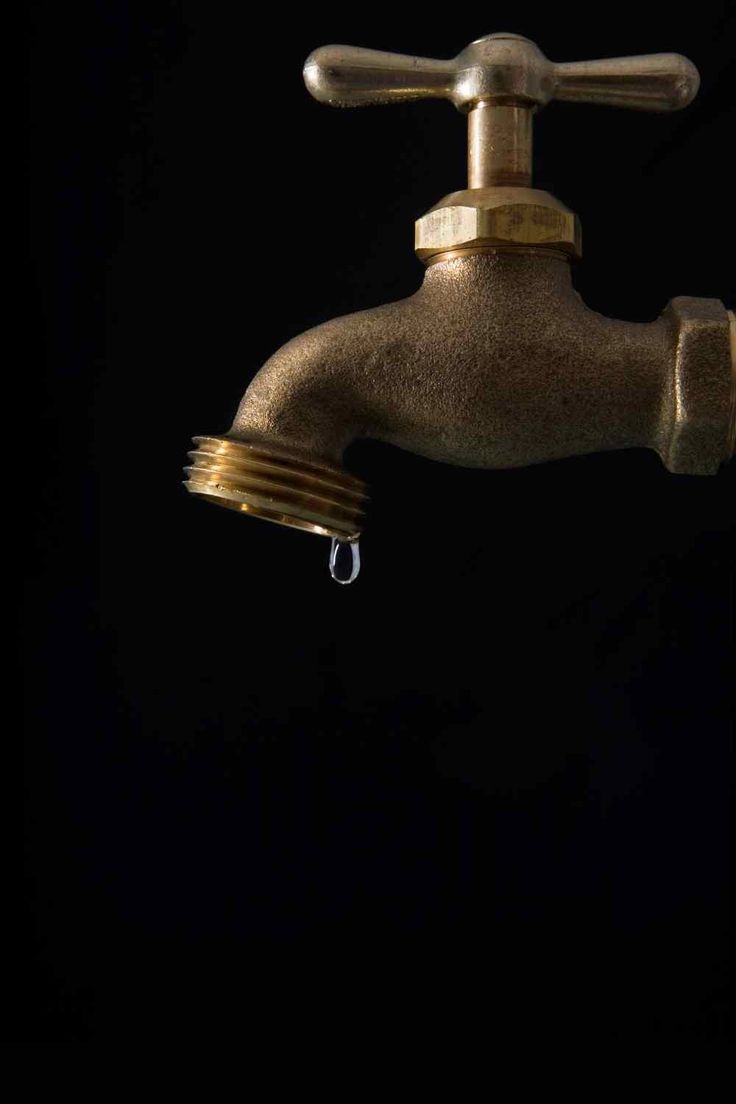 a faucet with water dripping from it's spout in the dark